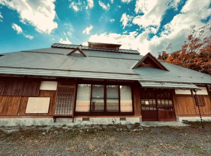 秋空の下に建つ古民家RINNEの外観。瓦屋根と木造の建物